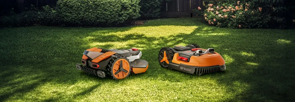 Zwei Mähroboter auf grünem Rasen